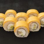 Makis au fromage fondants servis sur une assiette en bois avec des baguettes.