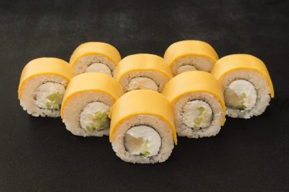 Makis au fromage fondants servis sur une assiette en bois avec des baguettes.