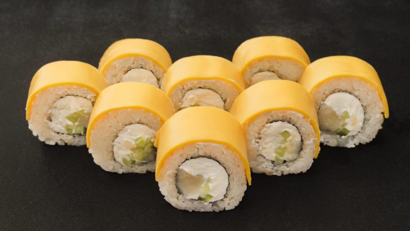 Makis au fromage fondants servis sur une assiette en bois avec des baguettes.