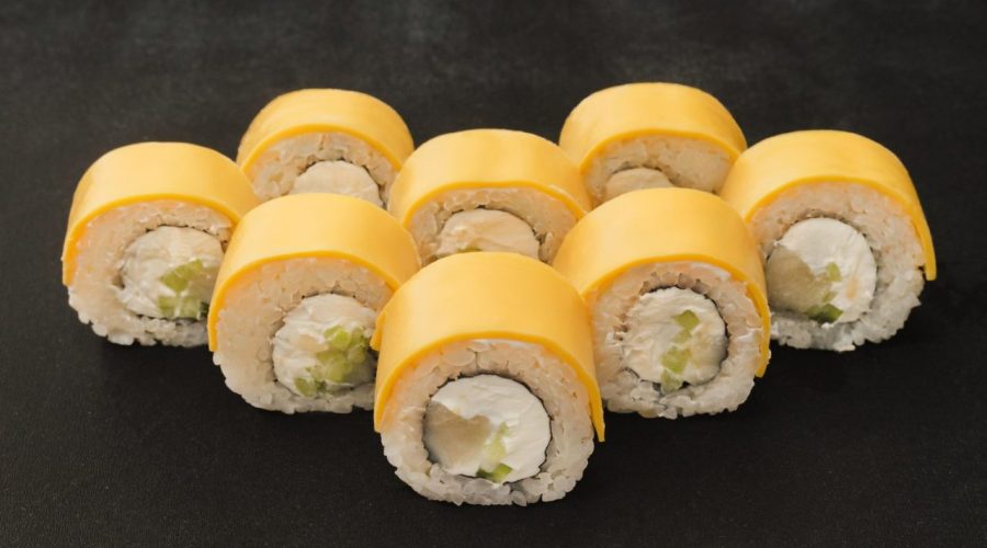 Makis au fromage fondants servis sur une assiette en bois avec des baguettes.